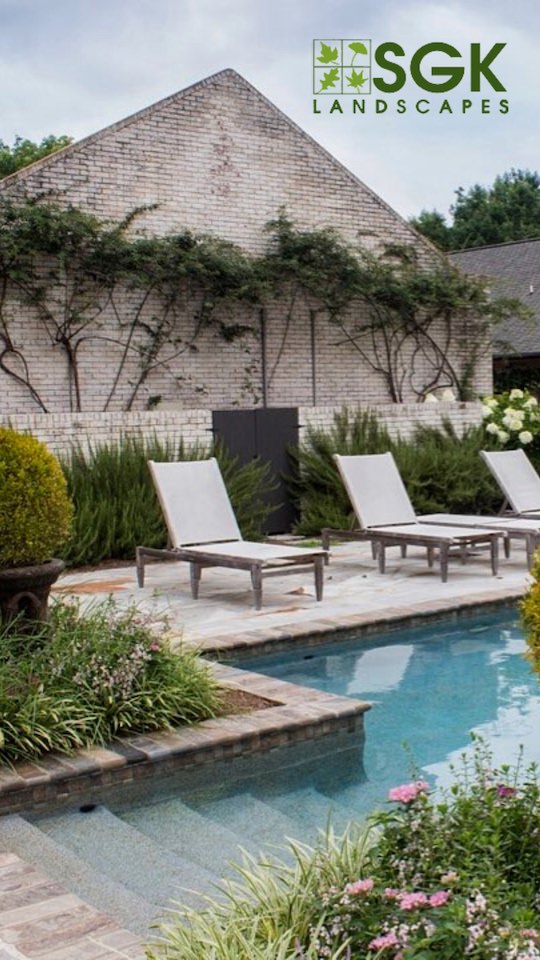 A backyard pool with lawn chairs and flowers