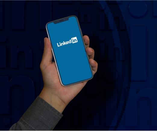 https://sociallyin.com/wp-content/uploads/2024/09/male-hand-holds-smart-phone-with-linkedin-logo-screen.png