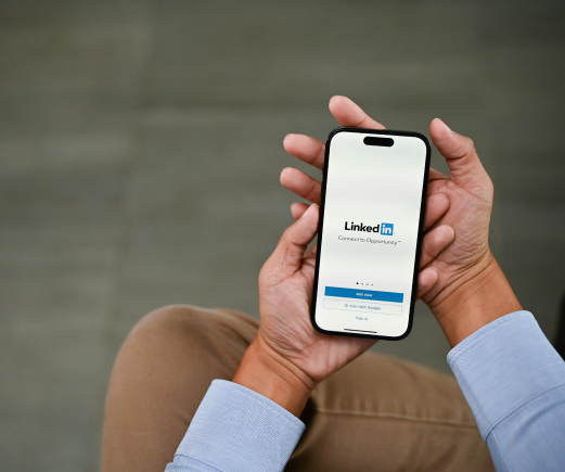 https://sociallyin.com/wp-content/uploads/2024/09/man-using-linkedin-his-iphone-linkedin-logo-iphone-screen-mockup-1.png