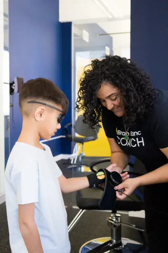 A coach fitting a wrist sensor on a boy wearing visual-training glasses