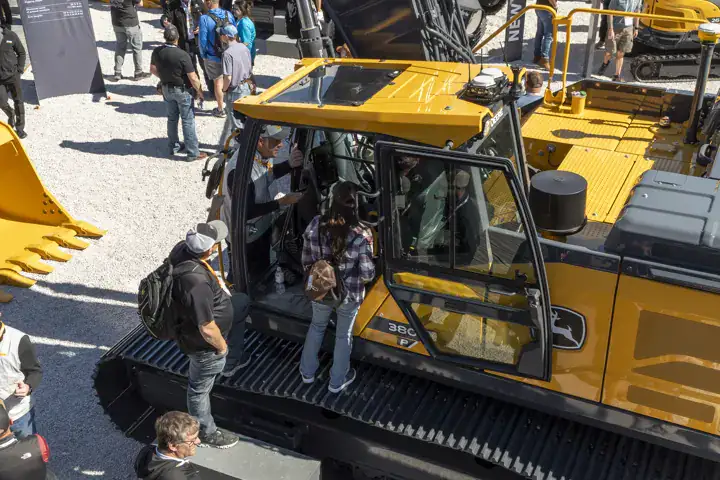 Attendees climbing a John Deere excavator